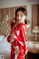 A woman in a red kimono standing on a bed.