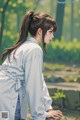 A woman in a white shirt is sitting on a rock.