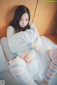 A woman sitting on a bed with a teddy bear.