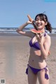 A woman in a purple bikini holding a slice of watermelon.