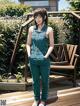 A woman in a blue jumpsuit standing on a wooden deck.