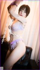 A woman in a purple lingerie is posing on a swing.