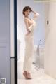 A woman in a white dress standing in a bathroom.