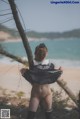 A woman standing on a beach next to a tree.